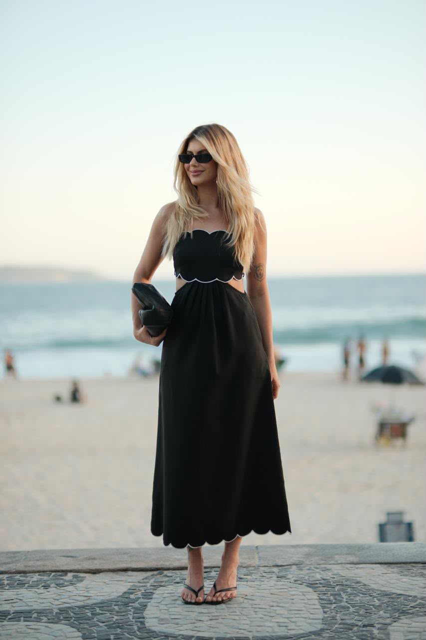Produção com vestido preto fotografada à beira-mar